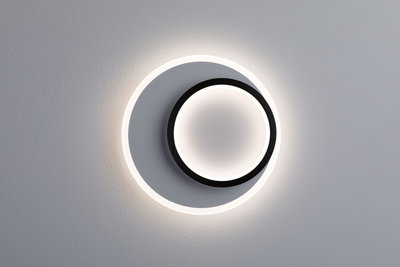 Modern round LED wall light in black and white with indirect lighting for living spaces