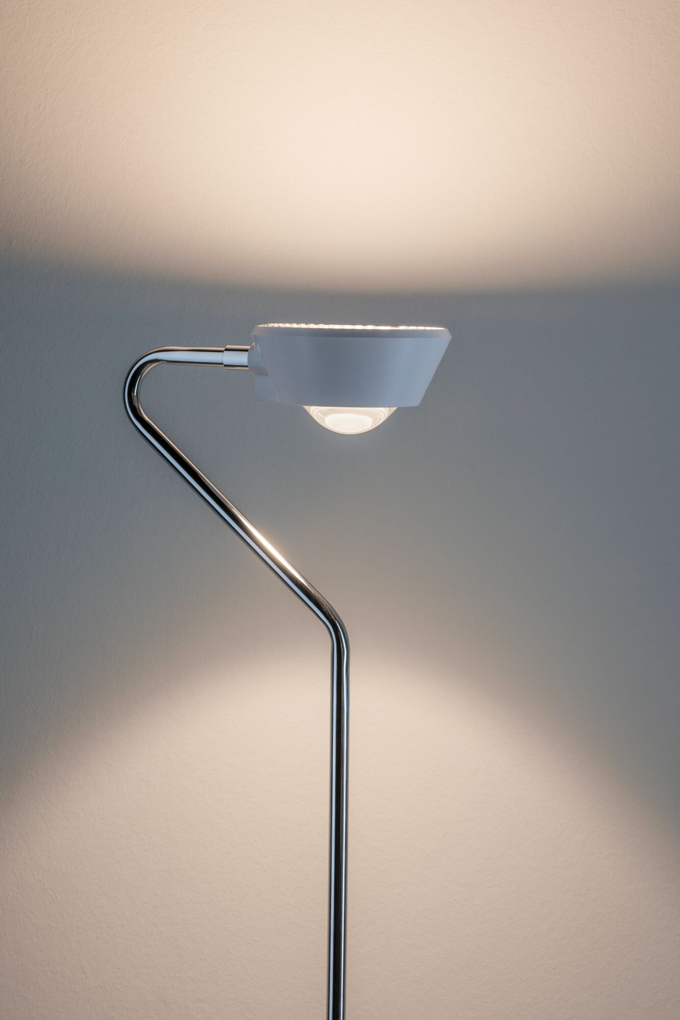 Moderne vloerlamp met witte kap en gebogen chromen standaard voor stijlvolle verlichting