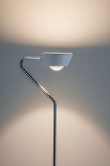 Moderne vloerlamp met witte kap en gebogen chromen standaard voor stijlvolle verlichting