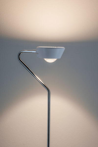 Moderne vloerlamp met witte kap en gebogen chromen standaard voor stijlvolle verlichting