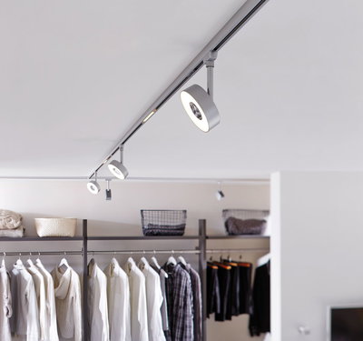 Modern white LED track light with round spotlights in a walk-in closet setting.