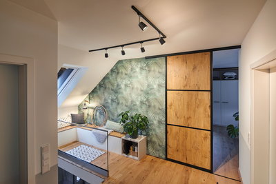 Moderne woonkamer met zwarte Paulmann LED-railverlichting en schuifdeur met houtdecor op groene muur.