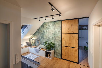 Moderne woonkamer met zwarte Paulmann LED-railverlichting en schuifdeur met houtdecor op groene muur.