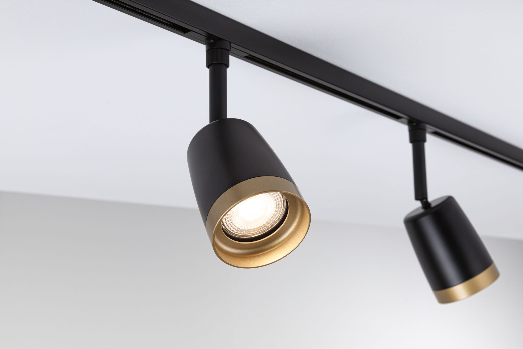Black LED spotlight with gold trim on track system for modern indoor lighting solutions