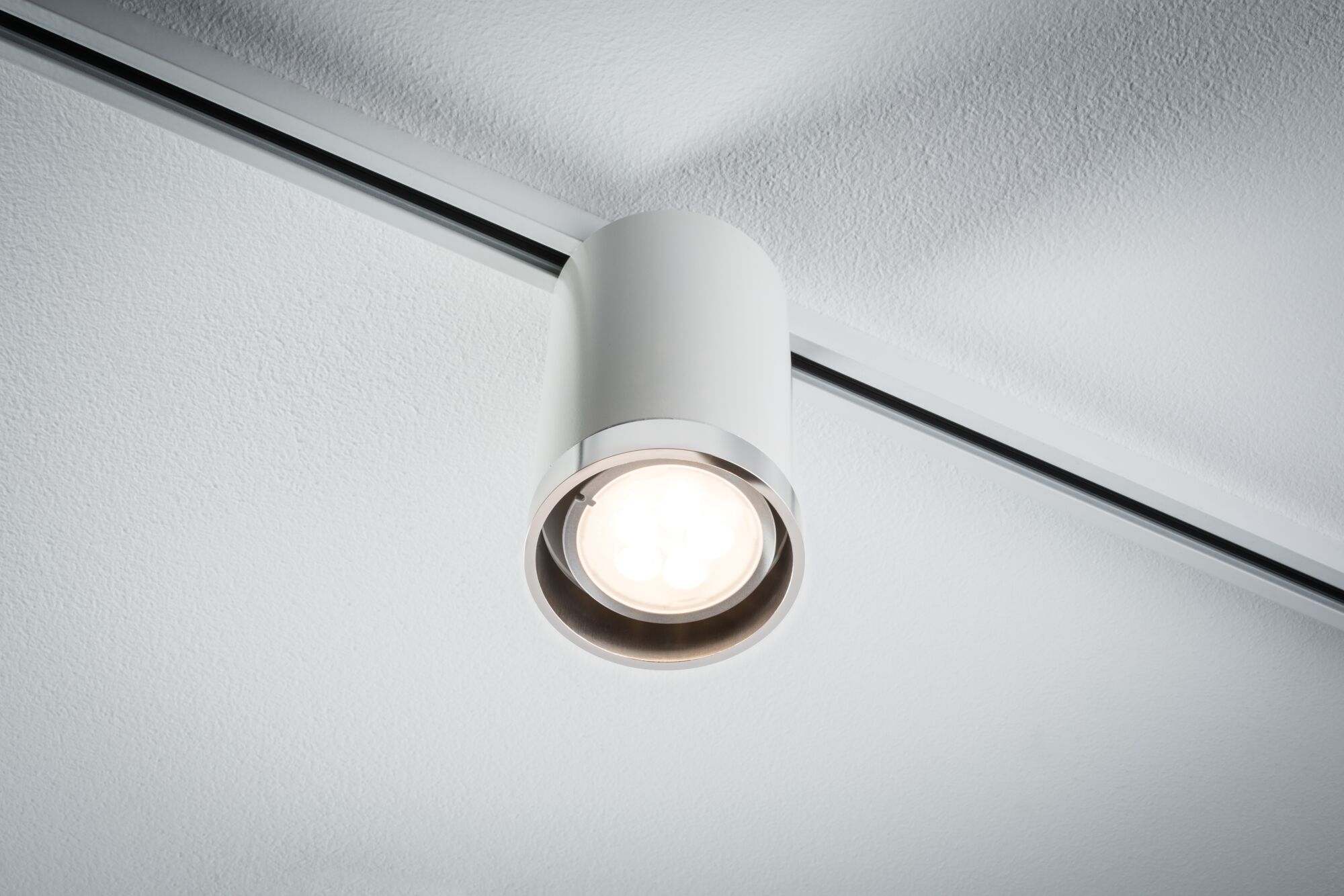 Weißer Deckenstrahler aus Metall mit LED-Licht an Schienensystem für moderne Innenbeleuchtung