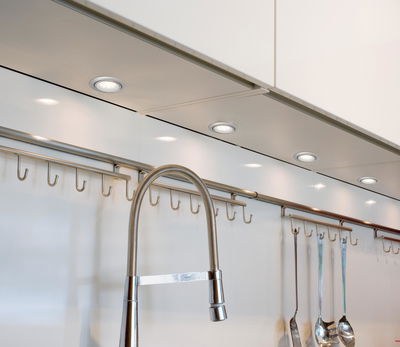 Moderne LED-Unterbauleuchten in Weiß mit Edelstahl-Küchenarmatur und Hakenleiste für Küchenutensilien