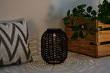 Black rattan solar lantern casting decorative light patterns, perfect for garden and patio lighting.