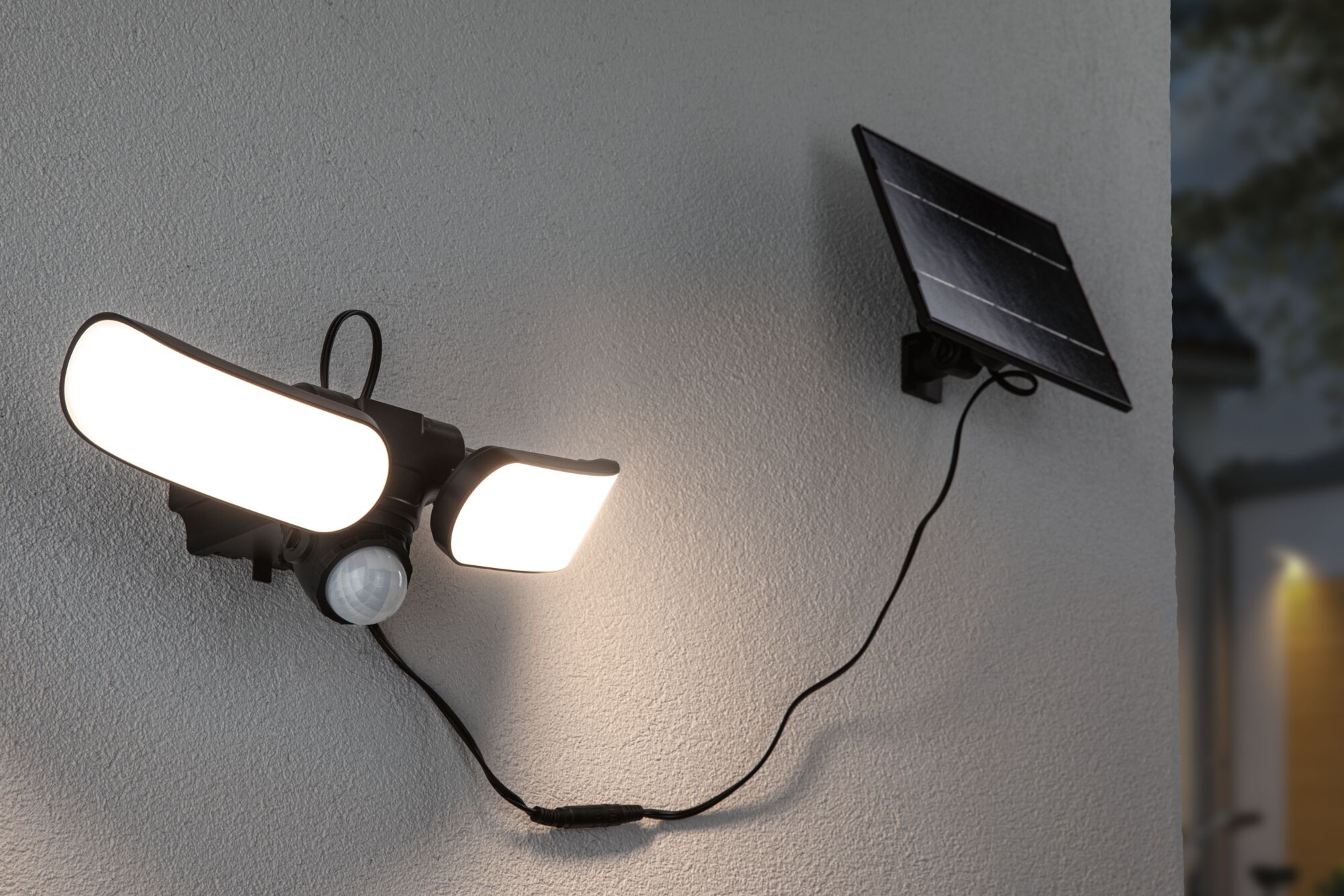 Black solar outdoor light with motion sensor and two bright LED panels mounted on white wall.