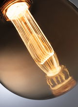 Close-up van warm gloeiende gloeilamp met bruin glas, geschikt voor decoratieve en vintage verlichting