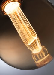 Nahaufnahme einer warm leuchtenden Glühbirne mit sichtbarem Filament in braunem Glas für dekorative Beleuchtung