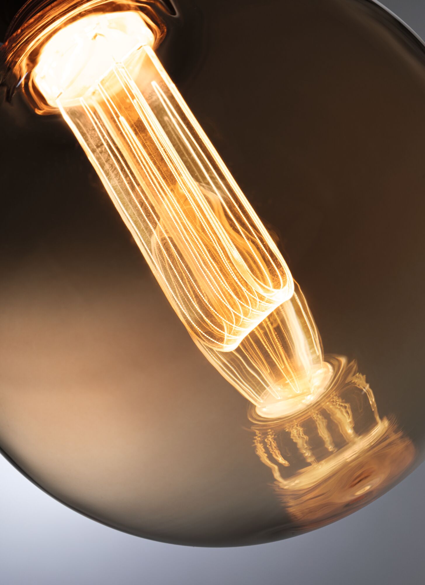 Nahaufnahme einer warm leuchtenden Glühbirne mit sichtbarem Filament in braunem Glas für dekorative Beleuchtung