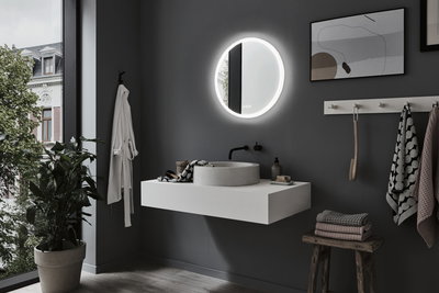 Moderne badkamer met ronde LED-spiegel, grijze muur, witte wastafel en houten kruk met handdoeken