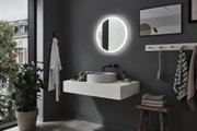 Round LED-lit bathroom mirror on grey wall above white basin in modern interior