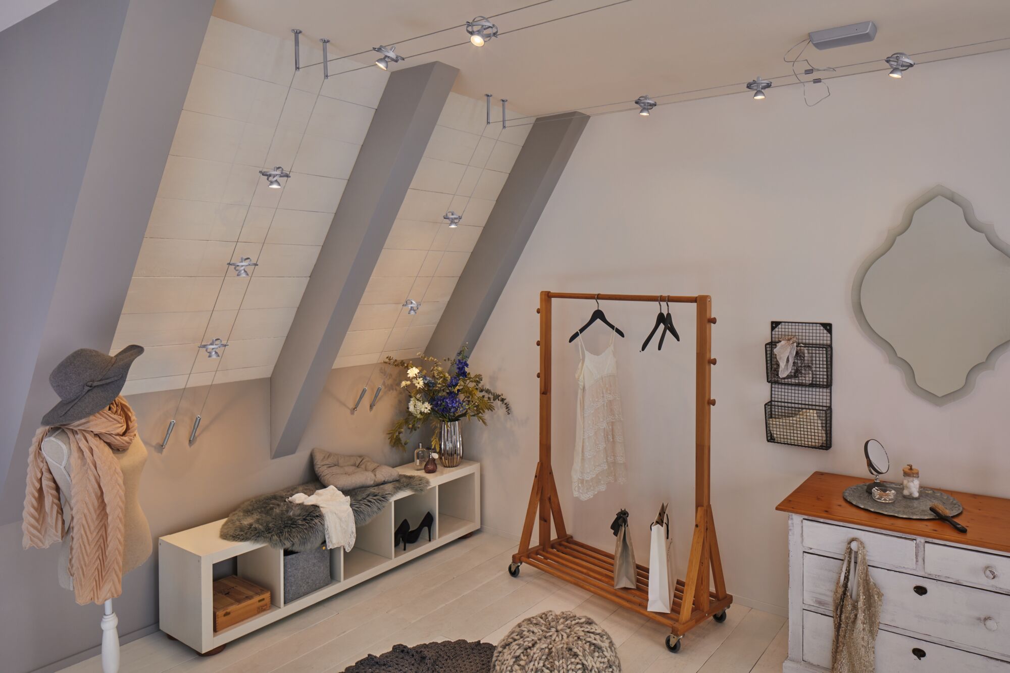 Moderner Raum mit Seil-Lichtsystem aus Metall in Silber, Holzkleiderständer und gemütlicher Deko im skandinavischen Stil