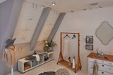 Moderne kamer met zilverkleurig metalen kabelverlichtingssysteem, houten kledingrek en gezellige Scandinavische inrichting