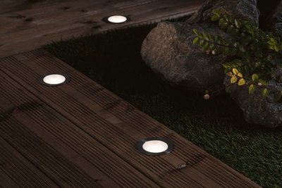 Round LED recessed floor lights with stainless steel frame on wooden terrace for garden lighting.