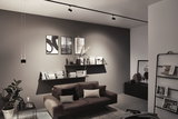 Modern living room with brown leather sofa, black wall shelves, and minimalist ceiling track lighting
