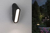 Schwarze LED-Außenwandleuchte mit länglichem Design an weißer Wand, Gartenbeleuchtung bei Nacht