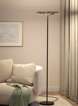 Schwarze Stehleuchte mit runder goldfarbener Leuchtfläche in modernem Wohnzimmer mit beige Sofa.