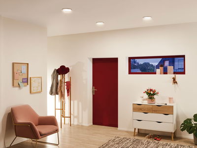 Modernes Wohnzimmer mit weißen LED-Einbaustrahlern, roter Tür und rosa Samtsessel mit goldfarbenem Gestell