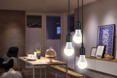 Drei weiße LED-Pendelleuchten mit schwarzem Sockel in modernem Esszimmer mit Holztisch und Dekoration