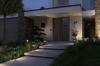 Modern outdoor lighting with black glass and wood lanterns along steps by house with natural stone wall.