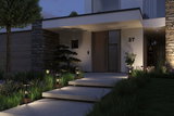 Éclairage extérieur moderne avec lanternes noires en verre et bois le long des marches devant maison en pierre naturelle.
