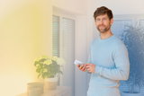 Man using white remote control for smart LED lighting in modern living room with plants