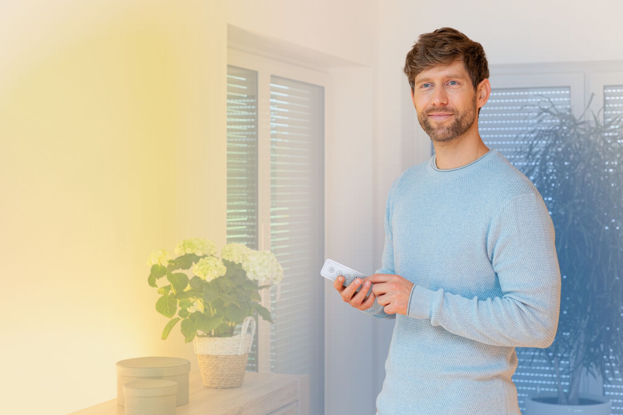 Mann steuert weiße Fernbedienung für smarte LED-Beleuchtung in modernem Wohnzimmer mit Pflanzen