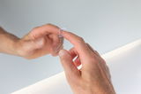 Hand touching transparent touch switch with light icon on white wall with LED lighting