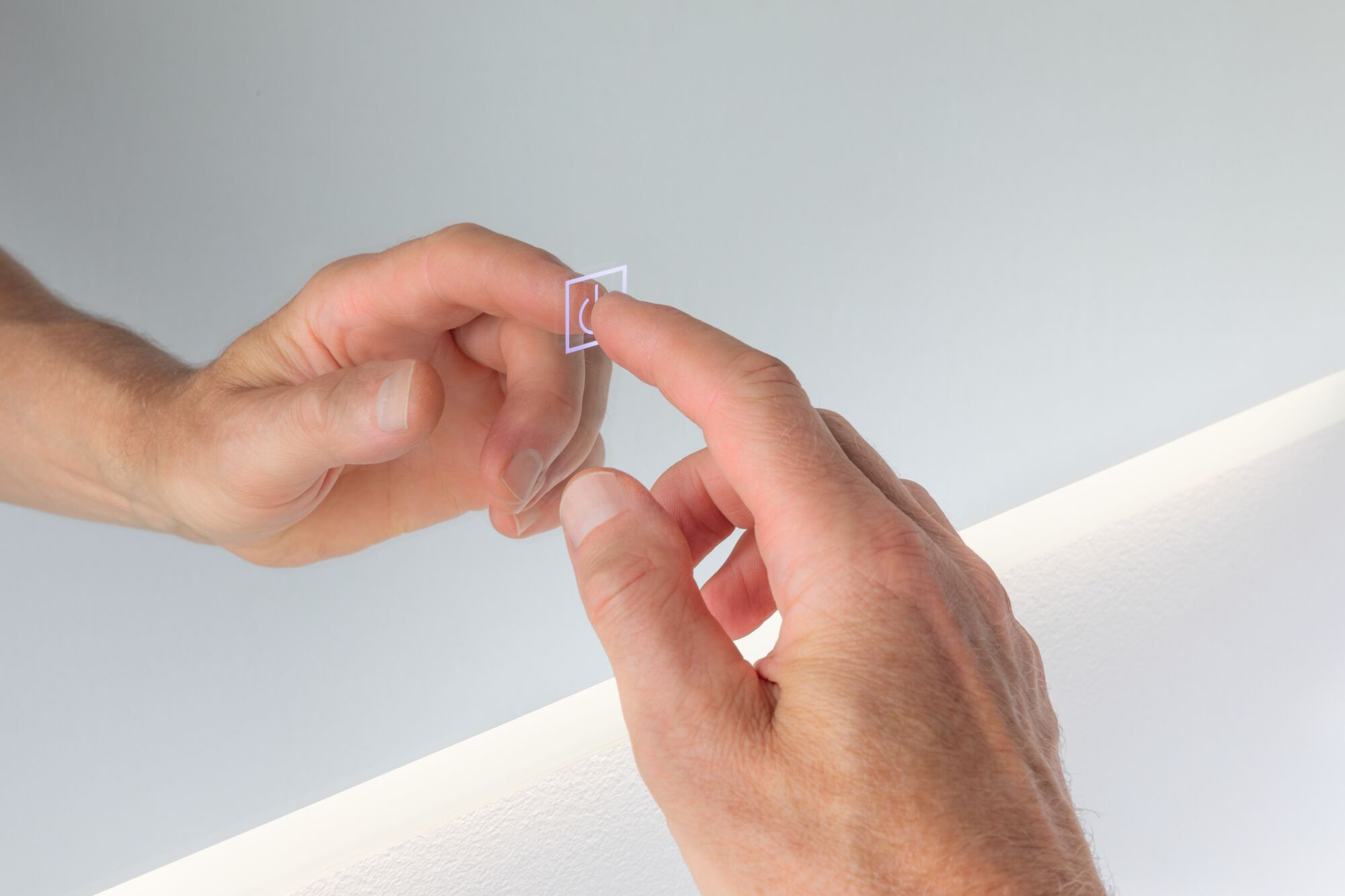 Hand berührt transparenten Touch-Schalter mit Lichtsymbol an weißer Wand mit LED-Beleuchtung