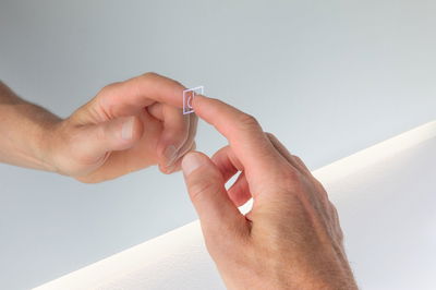 Hand berührt transparenten Touch-Schalter mit Lichtsymbol an weißer Wand mit LED-Beleuchtung