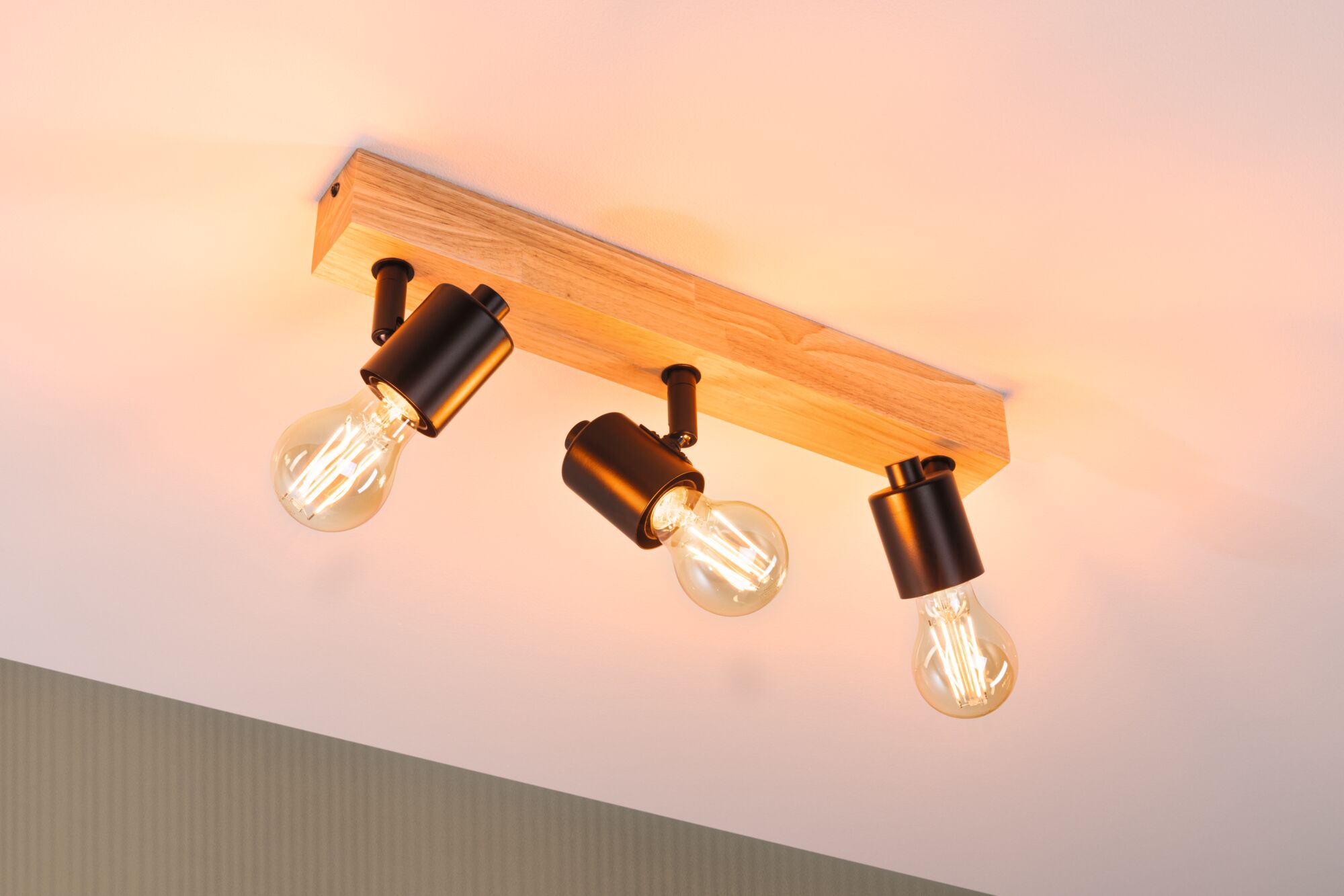 Deckenleuchte mit drei schwarzen Metalllampen an Holzleiste, warmweißes LED-Licht für Wohnräume