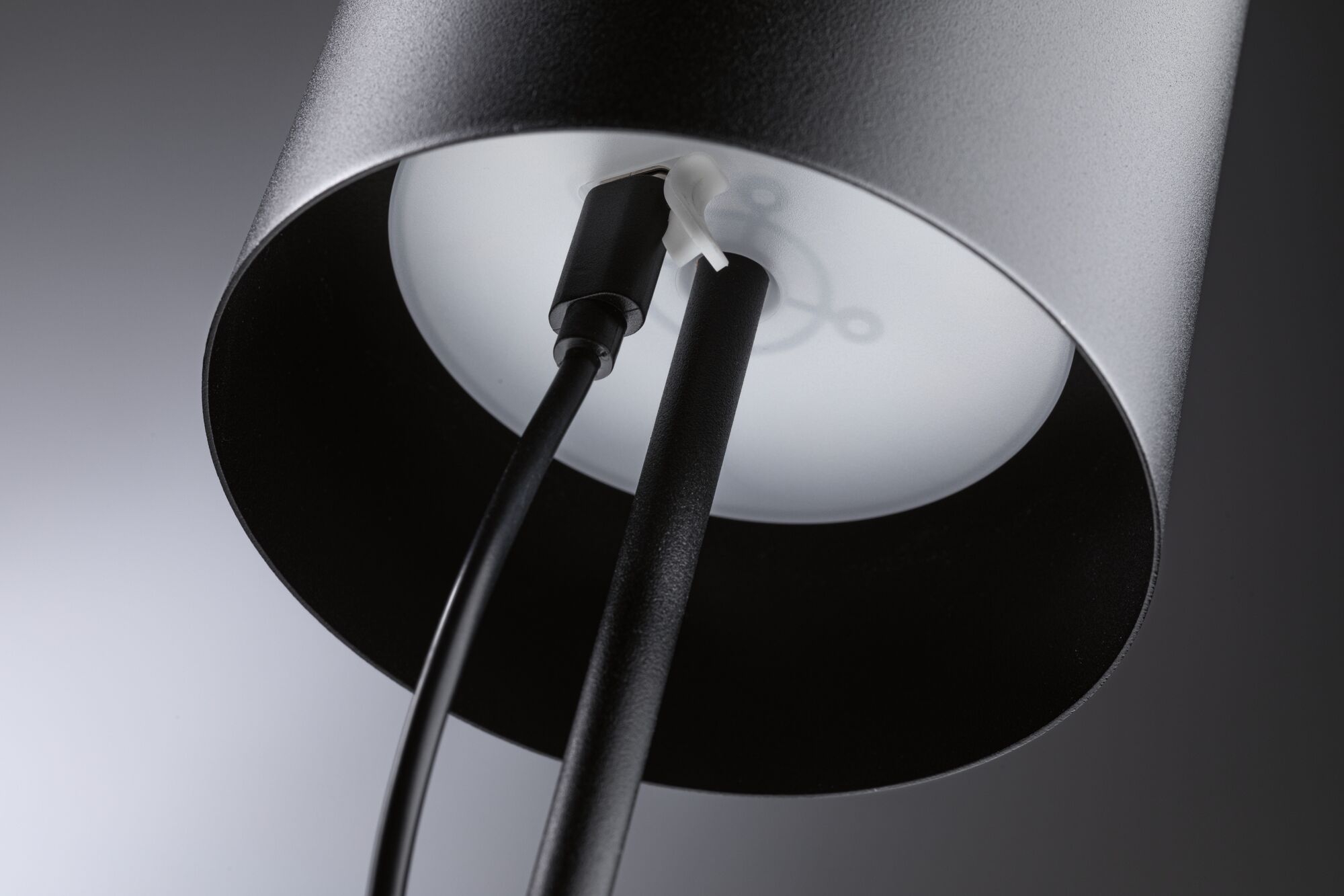 Lampadaire en métal noir avec câble et diffuseur blanc pour un intérieur moderne.