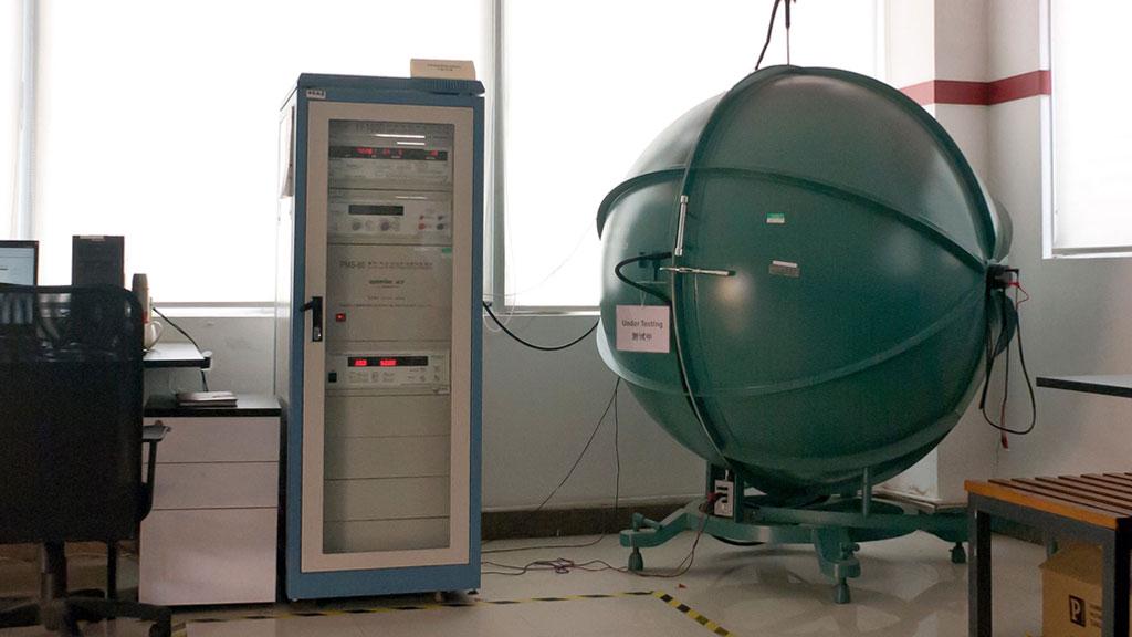 Large green spherical test chamber beside blue-white measuring device in lab for light quality testing.