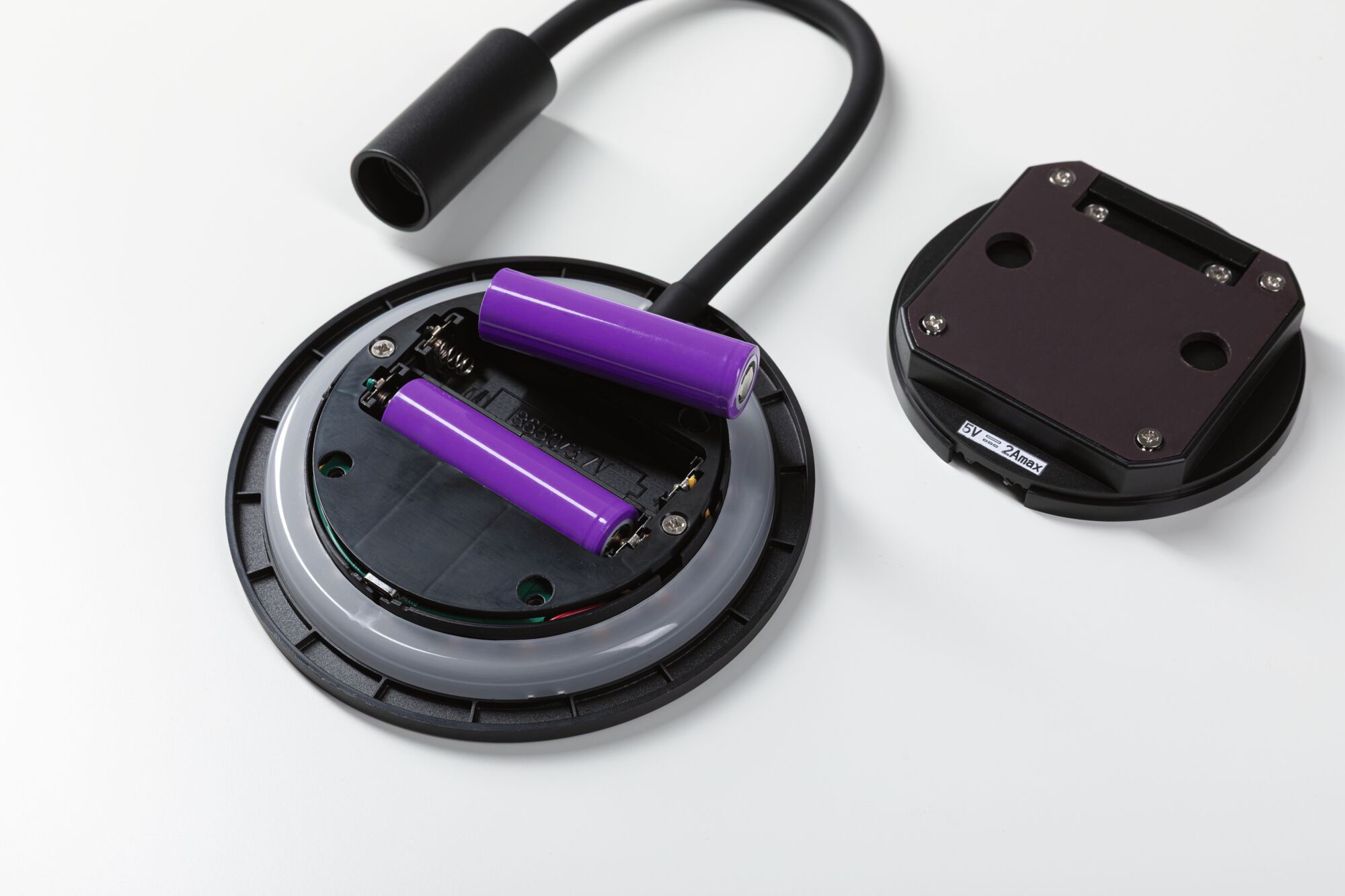 Open battery compartment with two purple lithium-ion batteries and black cable connector on white background