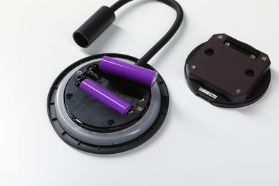 Open battery compartment with two purple lithium-ion batteries and black cable connector on white background