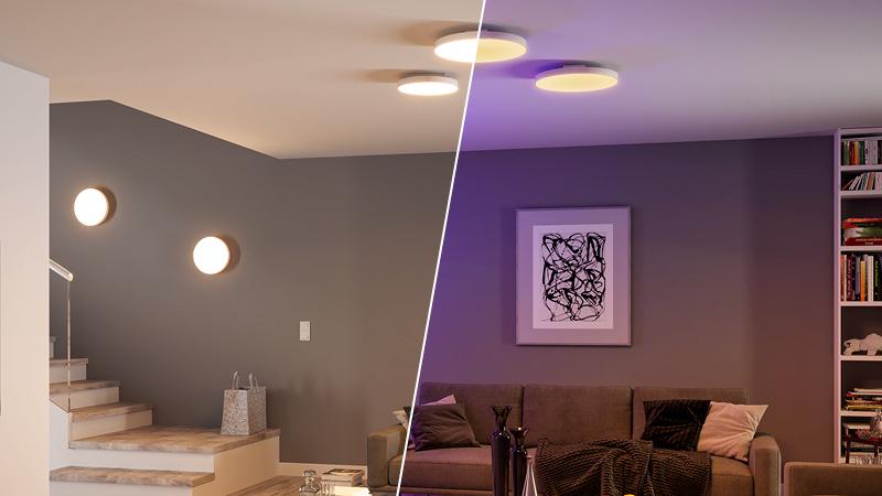 Moderne ronde plafond- en wandlampen met warm wit en gekleurd licht in woonkamer en trap.