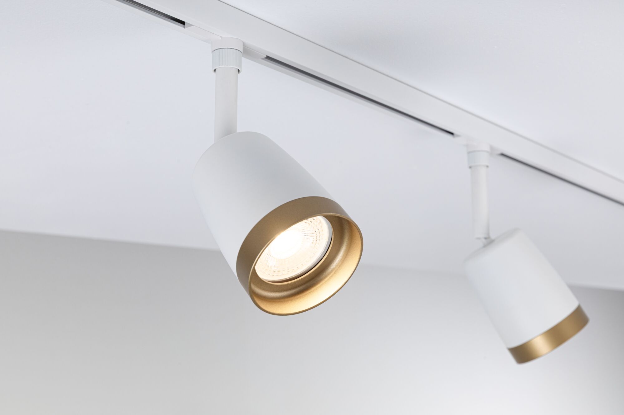 Modern white LED spotlight with gold trim on track system for focused room lighting