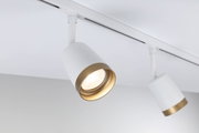 Moderner weißer LED-Spot mit goldfarbenem Rand an Schienensystem für gezielte Raumbeleuchtung
