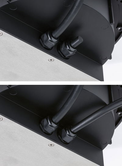 Close-up of black cable glands on black and silver metal housing for LED lighting fixture.