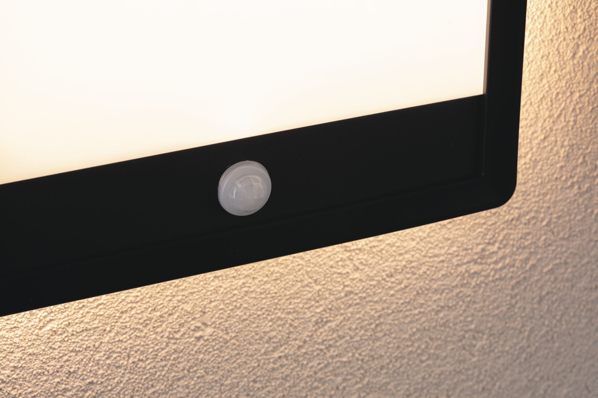 Applique murale LED noire avec détecteur de mouvement blanc fixée sur mur texturé pour éclairage