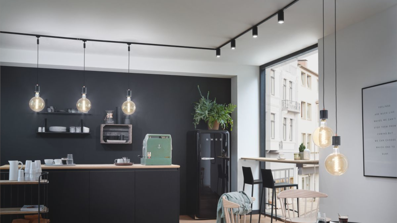 Moderne Restaurantbeleuchtung mit schwarzen Pendelleuchten und warmweißem Licht in elegantem Gastraum.