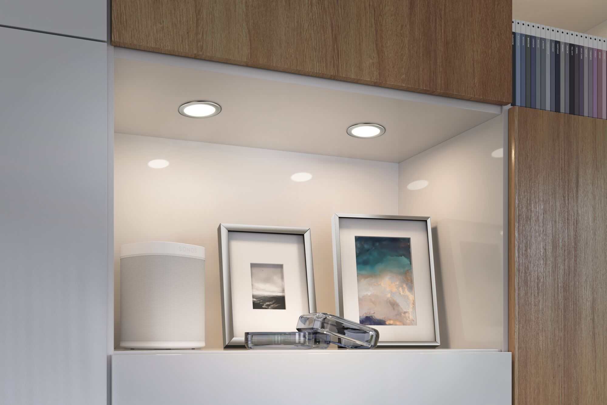 Two round white LED recessed lights with wooden shelf and decorative picture frames for home lighting.
