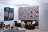Modernes Wohnzimmer mit indirekter MaxLED Deckenbeleuchtung in Tageslichtweiß und grauer Steinwand.
