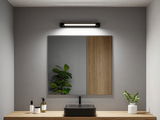 Black ceramic sink on wooden countertop with mirror and modern LED wall light in bathroom.