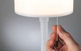 Hand zieht weißen Zugschalter an moderner weißer Tischlampe mit rundem Lampenschirm aus Kunststoff
