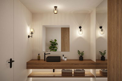 Modern bathroom with wooden vanity, black sink, and warm white glass wall lights for ambient lighting