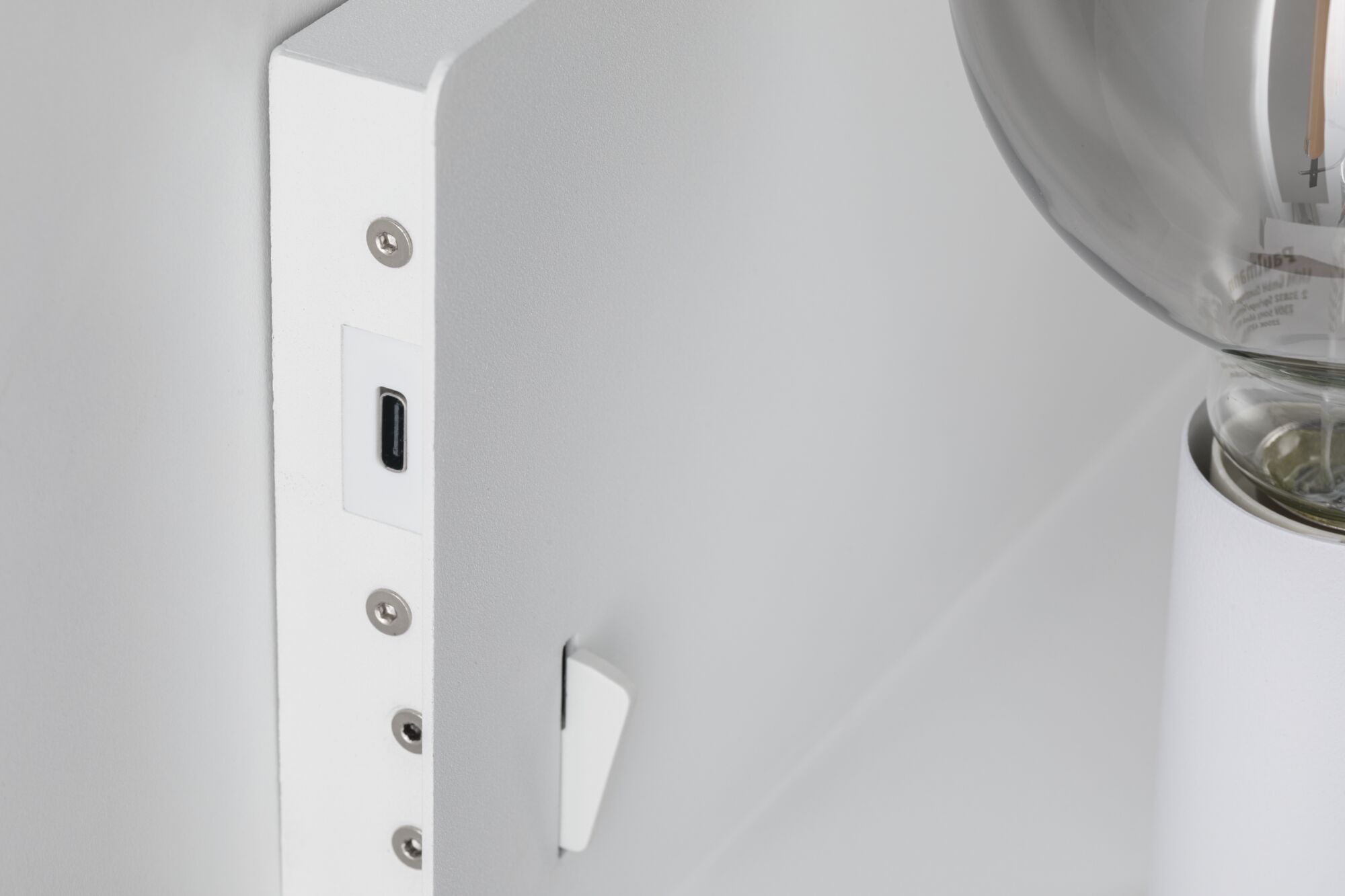 Nahaufnahme eines weißen Metall-Wandleuchters mit sichtbarem USB-C-Anschluss und Glühbirne.
