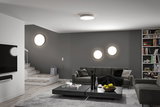 Modern living room with gray wall, gray sofa, and round white LED ceiling and wall lights for ambient lighting
